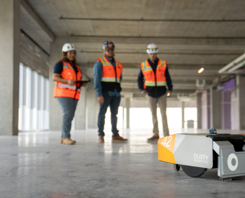 3 Swinerton employees holding remote that is driving the robot named Dusty