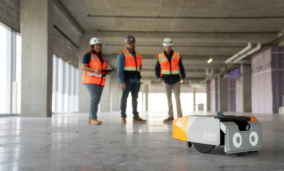 Dusty Robot 3 Swinerton employees holding remote that is driving the robot named Dusty